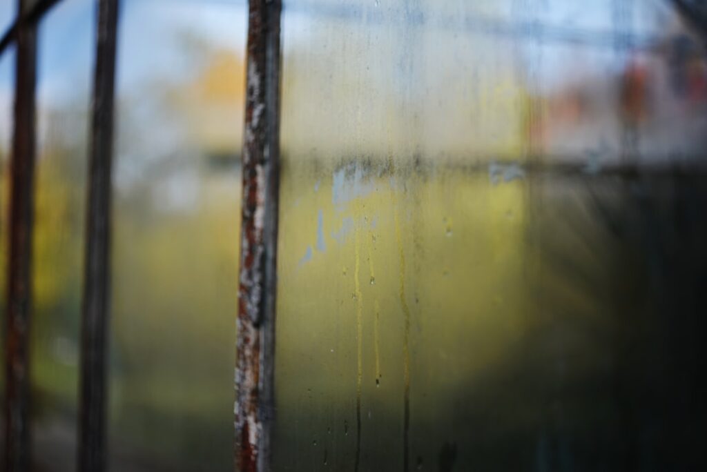 Close-up of RV technician applying silicone sealant around window frame with precision caulking gun, showing detailed moistur
