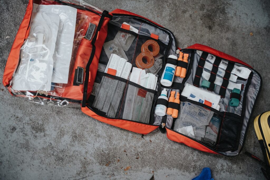 Overhead view of neatly organized RV emergency kit contents spread on clean surface, including first aid supplies, multi-tool