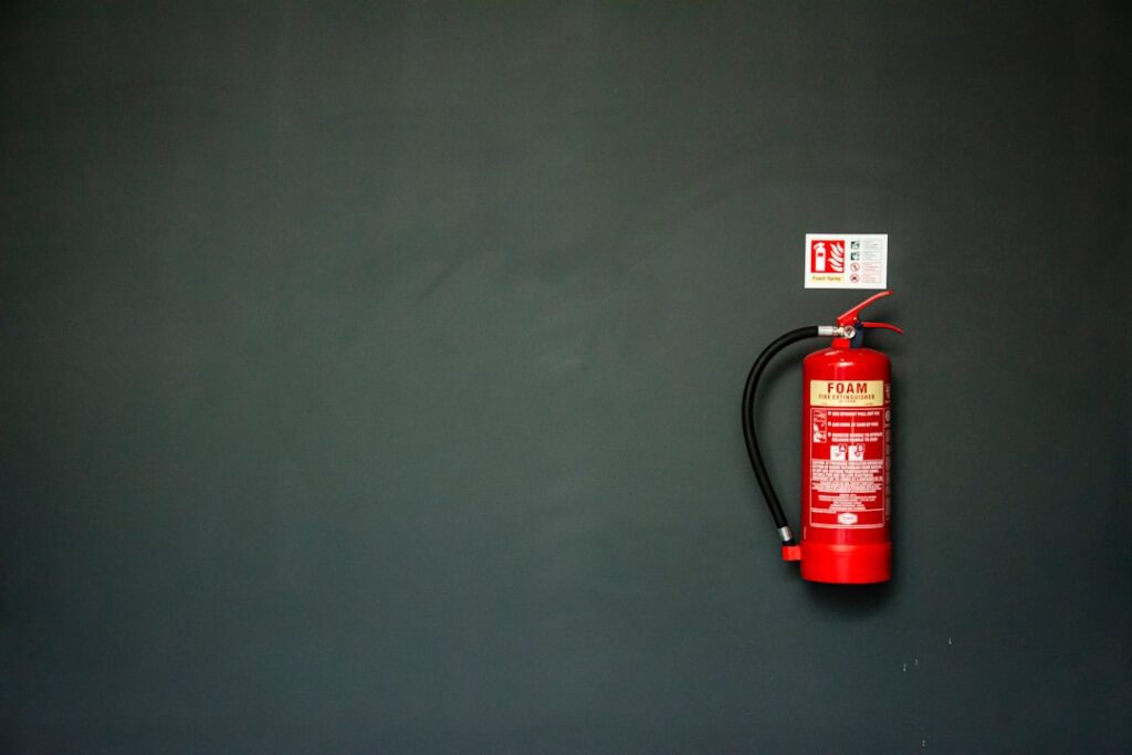 Close-up of hand holding fire extinguisher near RV kitchen area, showing proper mounting and easy accessibility