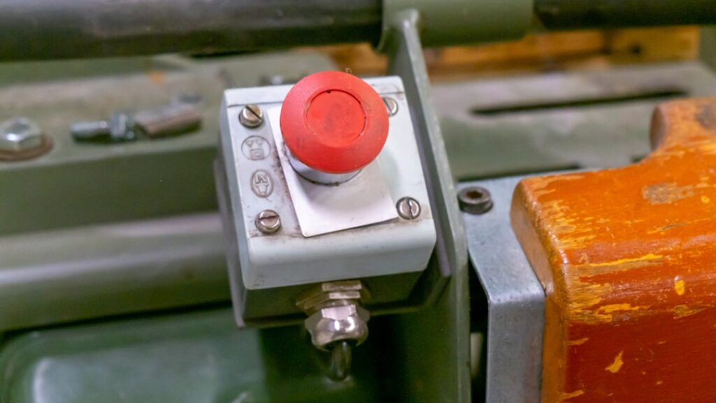 Close-up shot of a finger pressing the red test button on a white rectangular propane/LP gas detector mounted on an RV interi