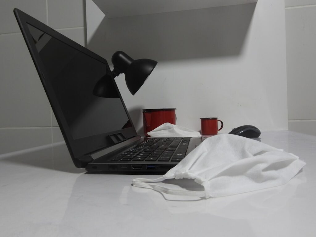 Close-up view of hands folding down a wall-mounted desk inside an RV, with a laptop computer, coffee mug, and small succulent