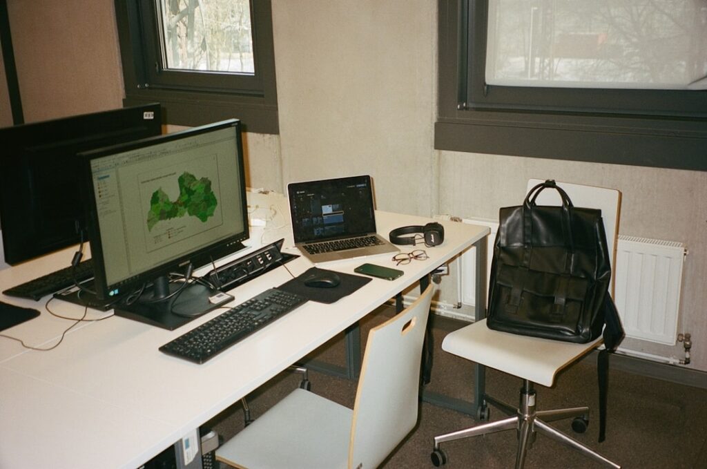 Close-up interior shot of an RV dinette converted into a professional workspace, showing a laptop on an adjustable table rise