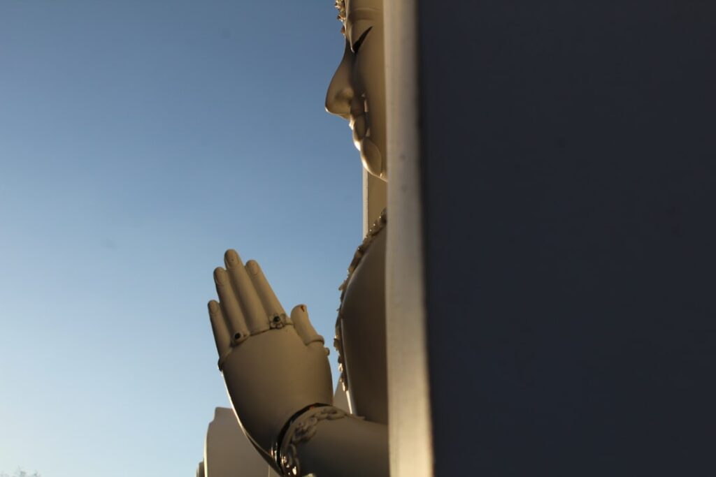 Close-up view of hands adjusting RV awning tension knobs while the awning extends over a perfectly organized outdoor campsite
